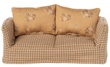 Beige checkered sofa with floral-patterned pillows on a beige background